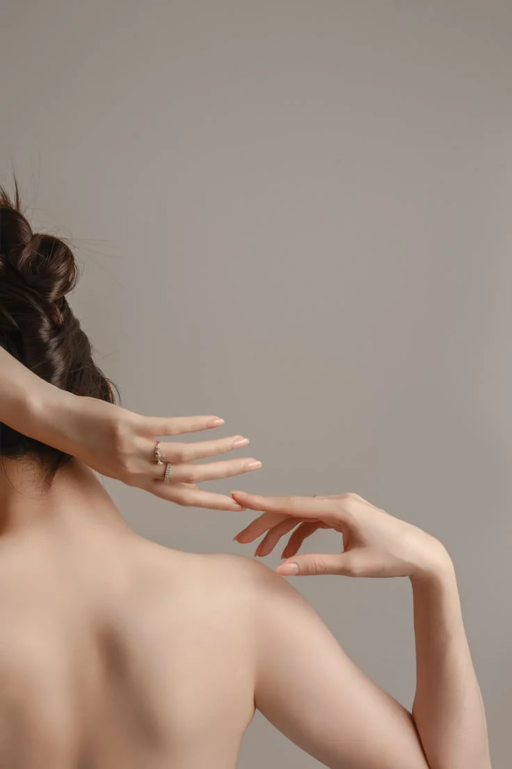 A woman's back and hands in soft studio light